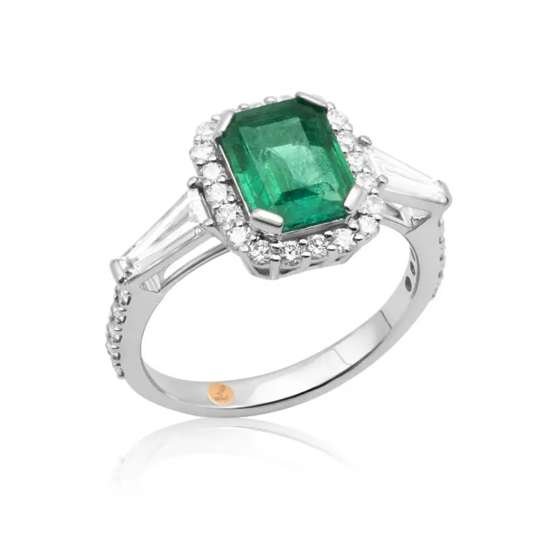 Emerald engagement ring with diamonds in the shape of tapered baguettes as side stones and a diamond halo.